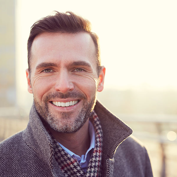 Man Smiling Outdoors in Coat