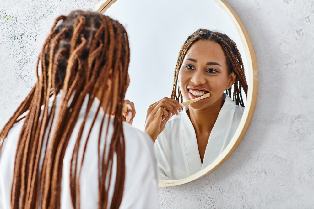 woman brushing her teeth in bathroom mirror