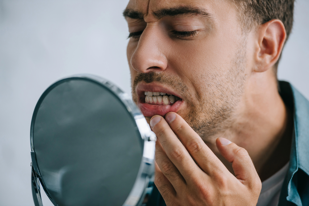 man looking at bottom teeth in a mirror