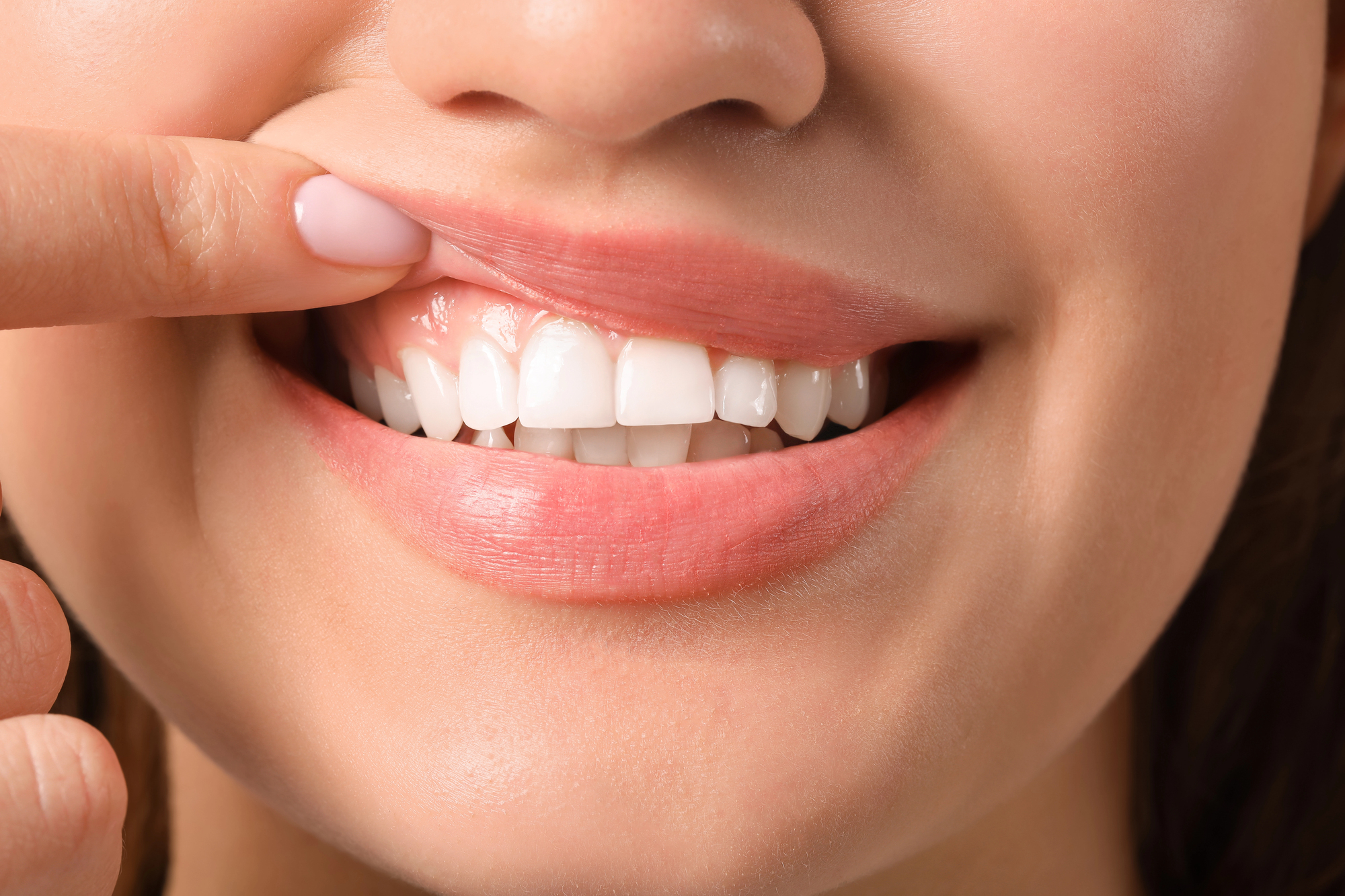A close-up image of a woman lifting her gum as if to contemplate, 