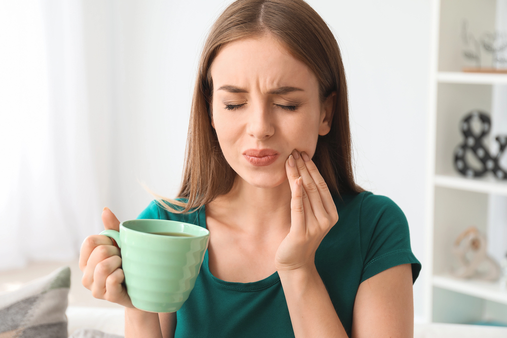 woman with tooth sensitivity drinking coffee