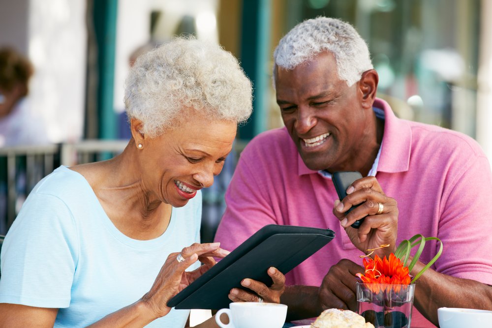 SeniorCoupleUsingTabletComputerAtOutdoorCafe Man with family after All-on-4 dental implants